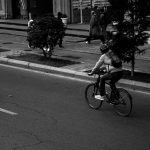 grayscale photo of man riding bicycle on road