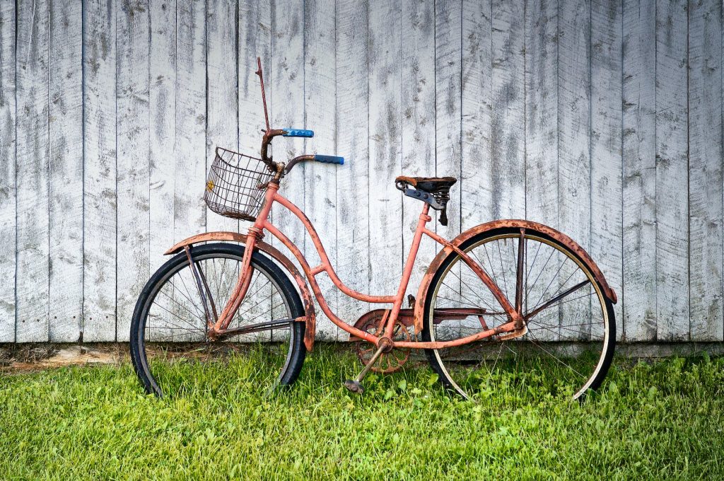 Vélo vintage dans l'herbe et contre palissade